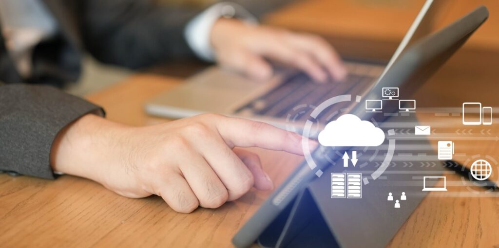Person in suit using a tablet with cloud computing icons, representing data transfer and digital connectivity concepts.
